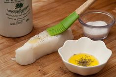 a wooden cutting board topped with food next to a cup filled with salt and seasoning