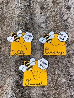 three bees with name tags on them sitting on the carpet in front of a pile of fake fur