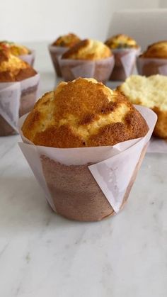 four muffins in paper cups on a table