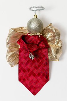 a red tie with gold wings and a silver ornament hanging from it's side