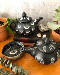 three teapots with faces painted on them are sitting next to some succulent plants