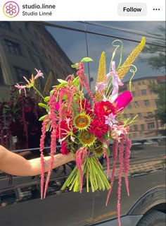 a person holding a bouquet of flowers in front of a car