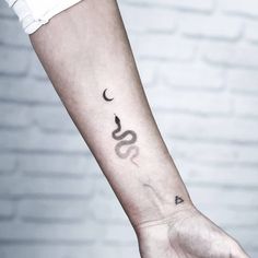 a person's arm with a snake and moon tattoo on the left side of their arm