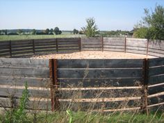 a fenced in area with an animal pen on the other side and grass around it