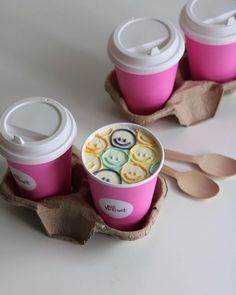 three coffee cups with lids and spoons sitting next to each other on a table