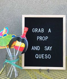 a sign that says grab a prop and say queso next to some utensils