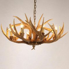 a chandelier with deer antlers hanging from it's sides and lit candles in the middle