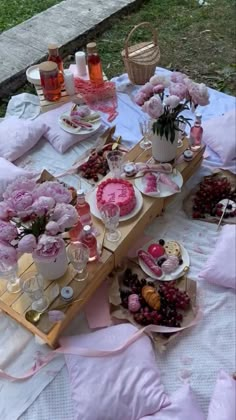 a picnic table is set up with pink flowers and desserts on it for a party