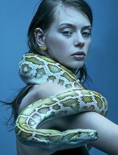 a woman is holding a large snake in her arms and posing for the camera with blue background