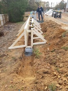 two men are working on the construction of a house with wooden posts and boards attached to it