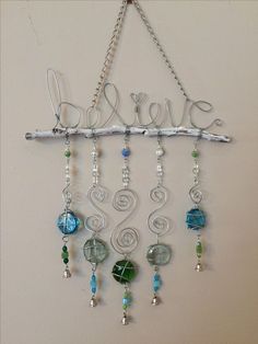 a metal sign that says believe hanging from a chain with beads and chains attached to it