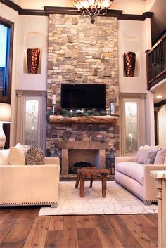 a living room filled with furniture and a flat screen tv mounted on the wall above a fire place