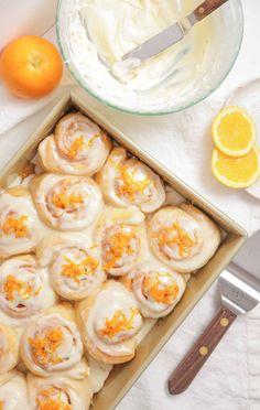 a pan filled with orange meringue rolls on top of a table next to an orange slice