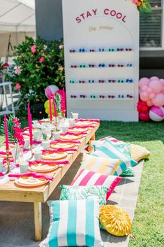 a table set up for a party with striped pillows and colorful napkins on it