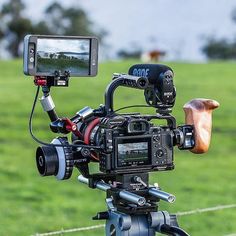 a camera attached to a tripod in front of a field