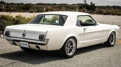 an old white mustang sitting in a parking lot