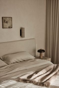 an unmade bed with white sheets and pillows