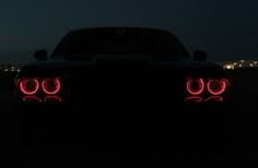 the tail lights of a black sports car at night