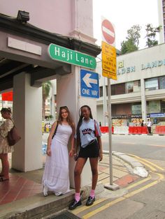 two young women standing next to a street sign