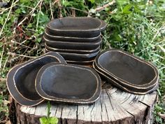 a stack of black plates sitting on top of a tree stump