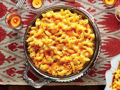 macaroni and cheese in a bowl on a table with candles, plates and forks