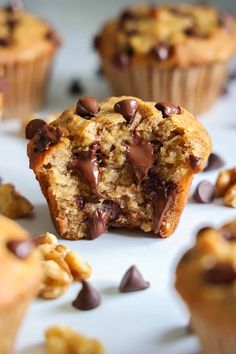 a muffin with chocolate chips and nuts on the top is sitting on a white surface