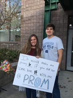 two people holding a sign in front of a building