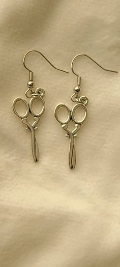 pair of scissors dangling from hooks on white fabric