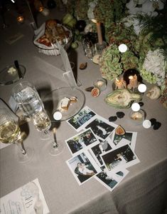 a table topped with pictures and candles next to wineglasses on top of a table