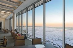 two people sitting on couches in front of large windows looking out onto the ocean