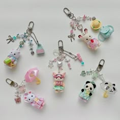 several keychains with various designs and colors are on a white surface, one has an animal charm in the middle