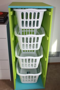 three white laundry baskets stacked on top of each other in a green cabinet with blue trim