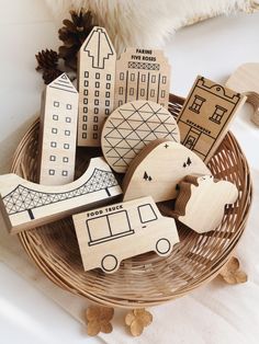 wooden cutouts in the shape of buildings and cars on a basket with pine cones