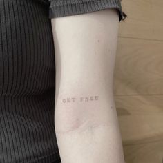 a woman's arm with the word get free tattooed on her left arm, in white ink