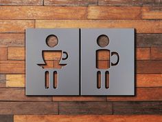 two metal signs on the side of a wooden wall that have coffee mugs in them