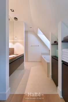 an attic bathroom with white walls and wood floors