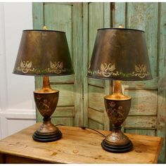 two lamps sitting on top of a wooden table next to a green wall and door