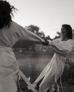 two women dressed in white are holding hands and pulling on the strings with their arms