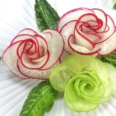 two flowers with green leaves on a white plate