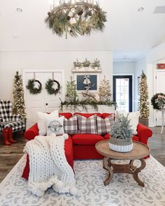 a living room decorated for christmas with wreaths on the wall and red couches