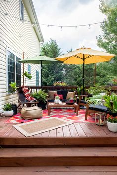 an outdoor deck with chairs, umbrellas and potted plants