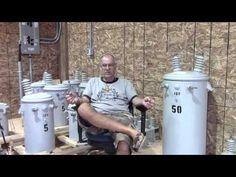 a man sitting in a chair next to some large electrical subwoeders and wires