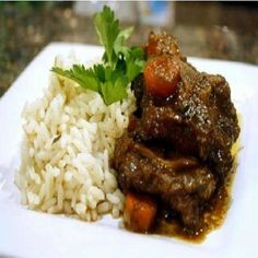 a white plate topped with rice and meat