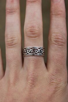 a woman's hand with a silver ring on top of her finger and an intricate design in the middle