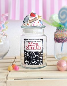 a glass jar filled with confetti and marshmallows on top of a wooden table