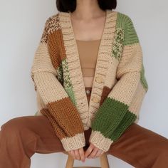 a woman sitting on top of a stool wearing a sweater and cardigan with multicolored stripes