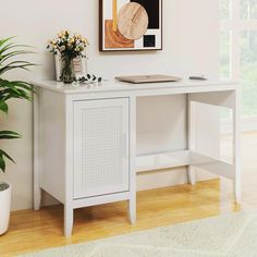 a white desk with a plant on top and a painting hanging above it in a living room