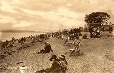 an old photo of people sitting on the beach