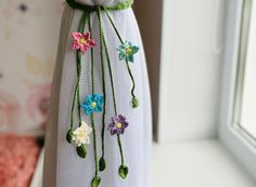 a white dress with flowers on it is hanging from a window sill in front of a wall