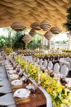 a long table is set up with yellow flowers and place settings for an outdoor event